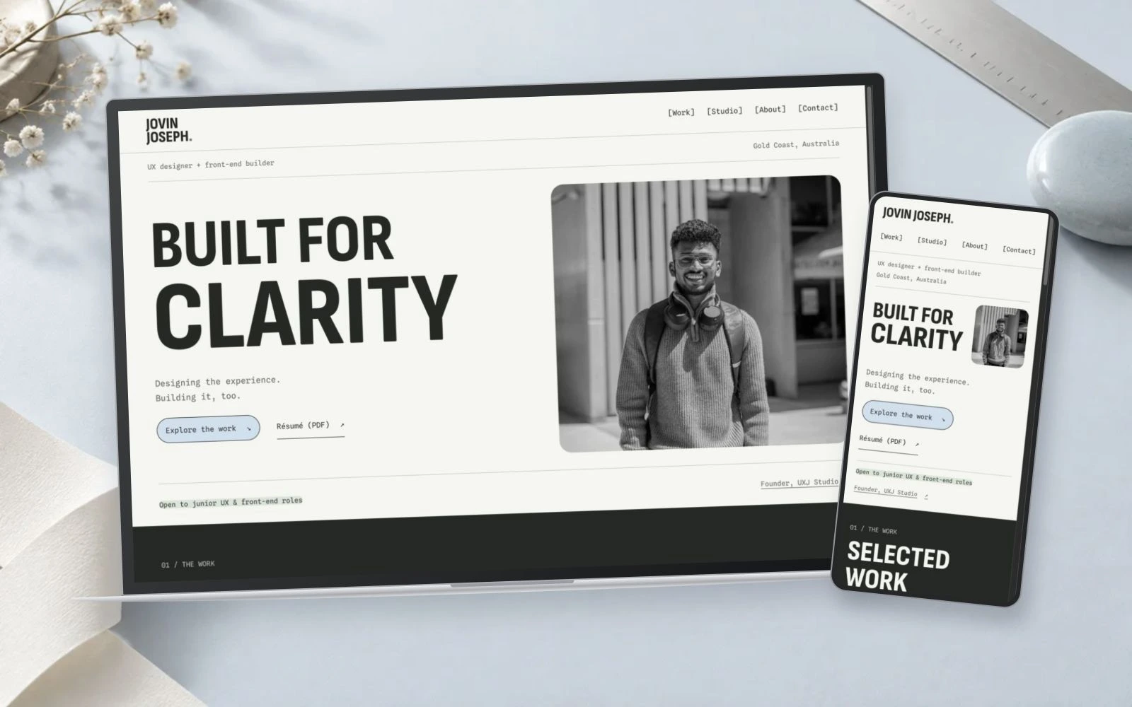 The current portfolio on a laptop and phone in a paper and powder-blue setting